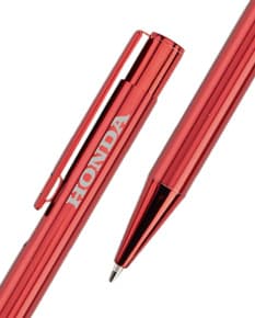 Caneta de metal colorida sobre fundo branco, ao lado de lápis e giz de cera. Imagem com diversos materiais de escrita e desenho, como forma de representar a criatividade e educação.