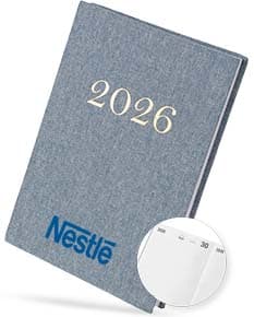 Notebook de linho para Agenda Diária 2026, com moderm à frente, equipamento eletrônico, livro, papel em branco, objetos de escritório, em destaque.