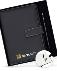 Conjunto executivo composto por notebook preto e bloco de notas de couro preto sobre uma mesa de escritório. O notebook está aberto, mostrando uma tela de dados e um teclado, junto com um dispositivo de armazenamento externo. O bloco de notas de couro está aberto, exibindo uma página em branco. Diversos itens de tecnologia, como drive externo, laptop, e disco rígido, estão presentes na imagem, juntamente com itens de papelaria, como caneta e papel. A imagem transmite uma sensação de modernidade e profissionalismo.