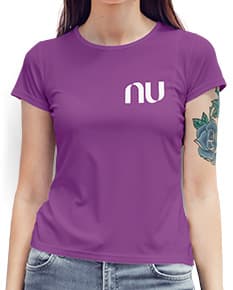 Camiseta feminina com uma garota atraente e sorridente, posando de forma casual em um estúdio. O modelo tem cabelos escuros e olhos expressivos, vestindo jeans. Ela transmite confiança e estilo.